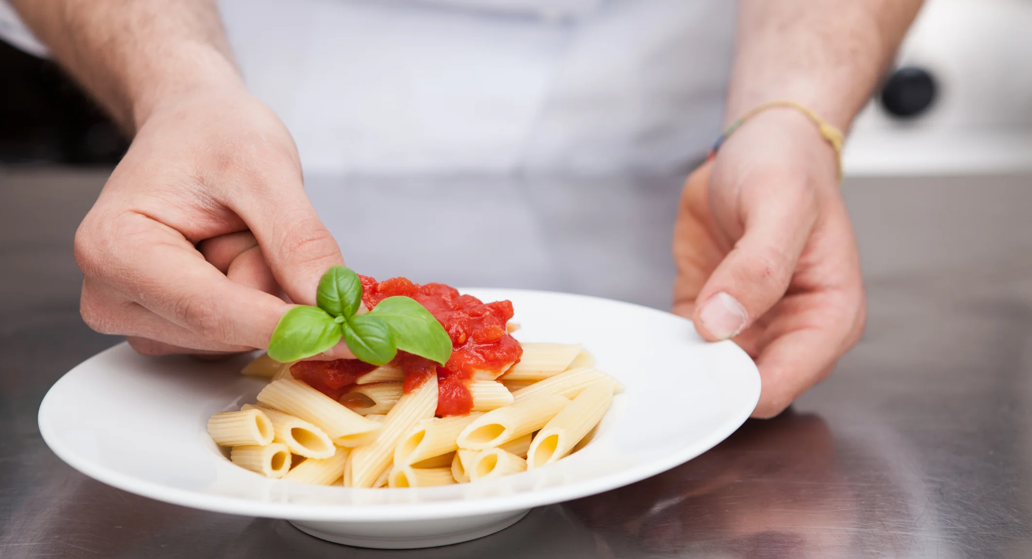Chef adding garnish to pasta dish