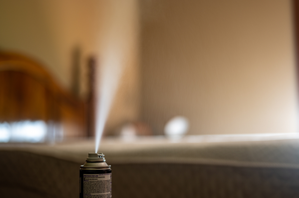 A bed bug fogger sprays insecticide over a bedroom.