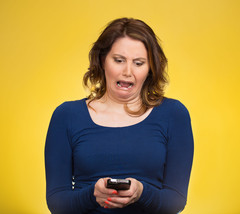 A person looking at their phone and making an unpleasant face.