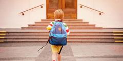 A child walking up the steps of their school.