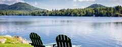 Two chairs by a lake on a sunny day.