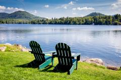 Two chairs by a lake on a sunny day.