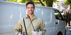 A pest control worker posing outside of their van.