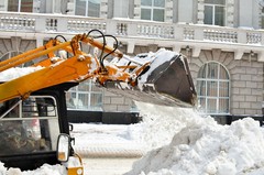 A bobcat clearing a parking lot of snow.