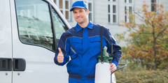 A pest control worker posing outside of a van.