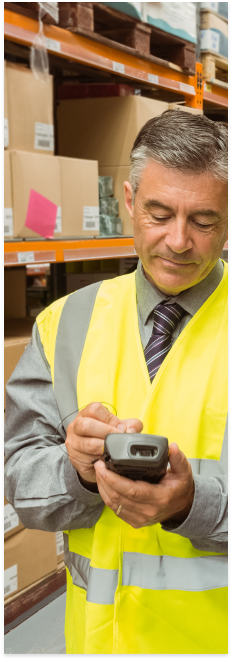 A person in a yellow vest in a warehouse.
