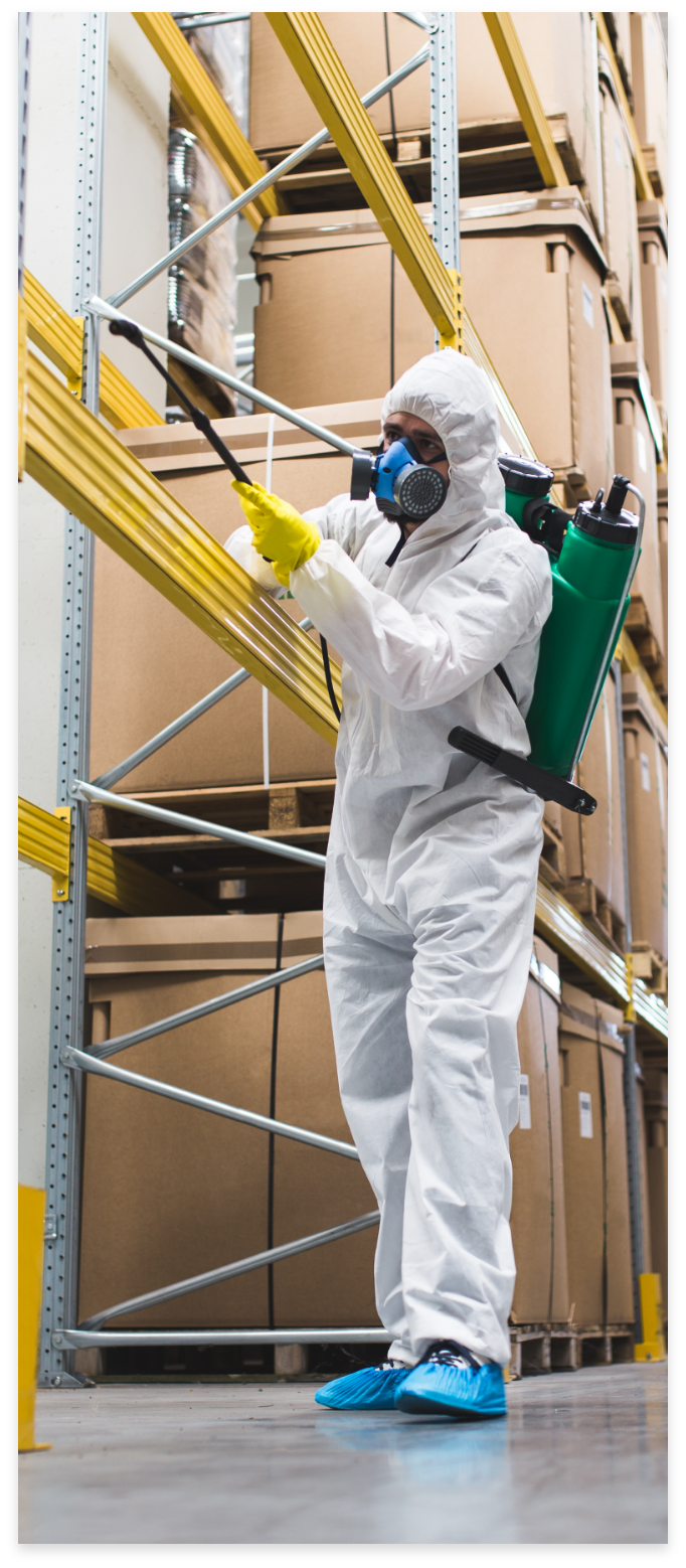 An exterminator spraying beams in a warehouse.